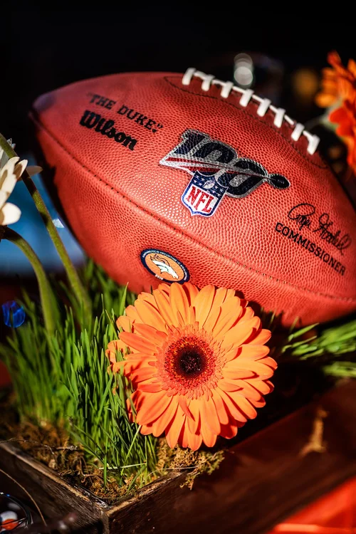 Denver Broncos football centerpiece detail with orange gerbera daisies corporate event photography