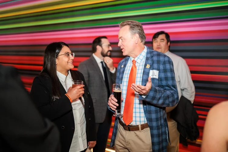 Guests talking at cocktail hour with colorful stripe mural backdrop Mission Ballroom Denver Colorado