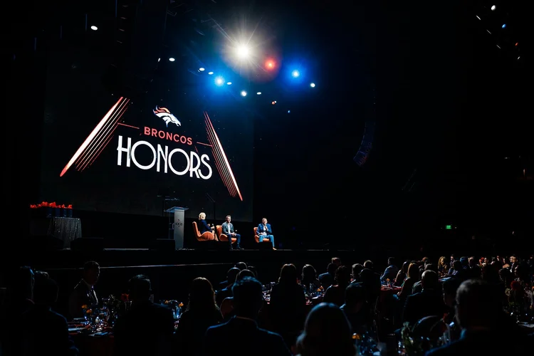 Full room view of Denver Broncos Honors Awards program with audience and Broncos Honors stage at Mission Ballroom