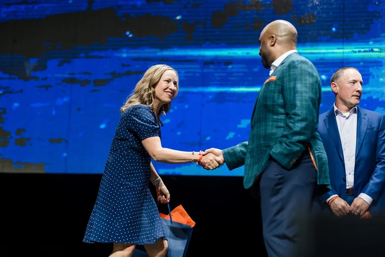 Award recipient handshake on stage at Denver Broncos Honors Awards Mission Ballroom Denver