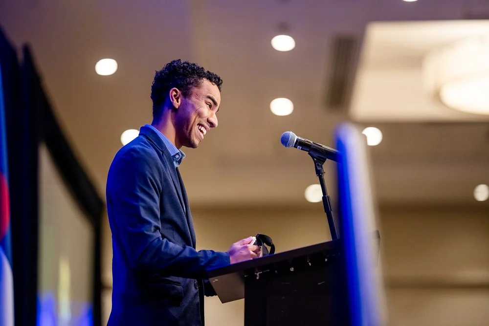 Young man at podium side profile laughing at CCA Annual Luncheon Hyatt Regency Aurora Denver Colorado
