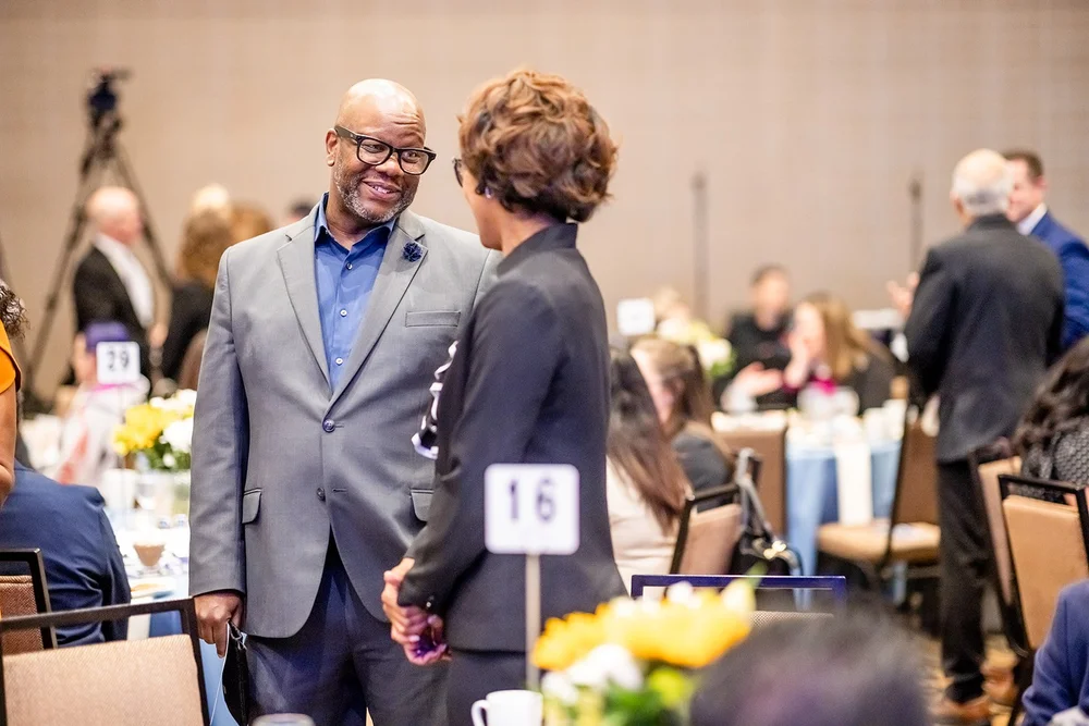 Man in grey suit shaking hands with an attendee at CCA Annual Luncheon fundraiser Hyatt Regency Aurora Denver