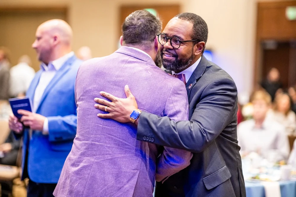 Two men embracing in greeting at CCA Annual Luncheon Hyatt Regency Aurora Colorado