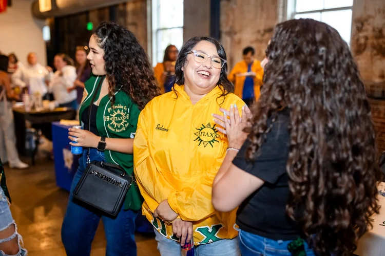 Pi Alpha Chi sorority member laughing with prospective student at Meet the Greeks MSU Denver