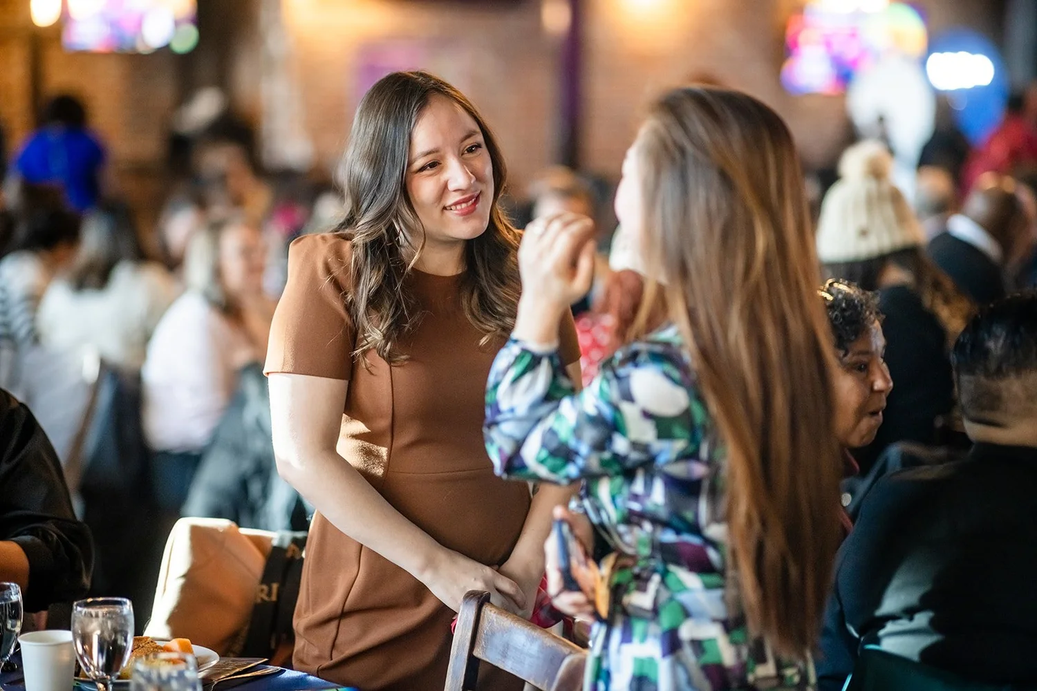 Two women in conversation at table MLK Peace Breakfast Mile High Station Denver Colorado