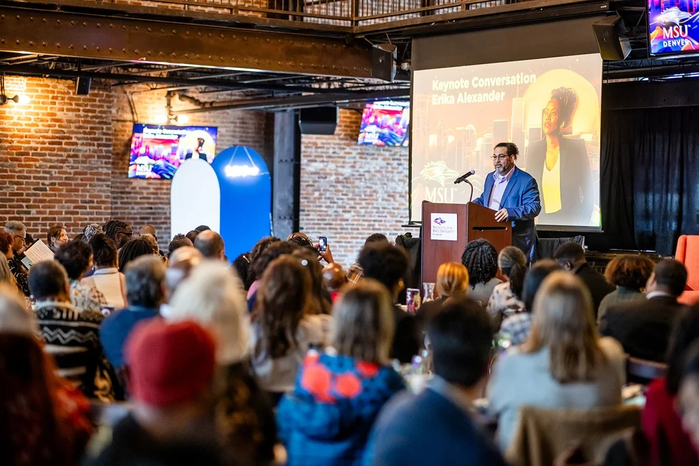 Wide room view of MSU Denver MLK Peace Breakfast with keynote Erika Alexander slide on screen Mile High Station Denver