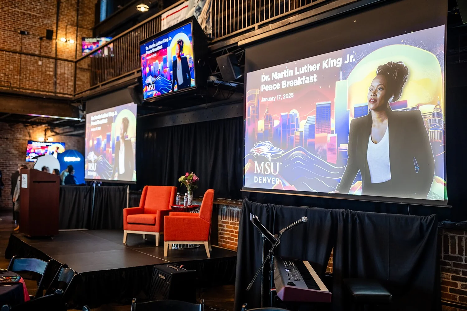 Stage setup before MSU Denver MLK Peace Breakfast at Mile High Station with orange chairs and projection screens