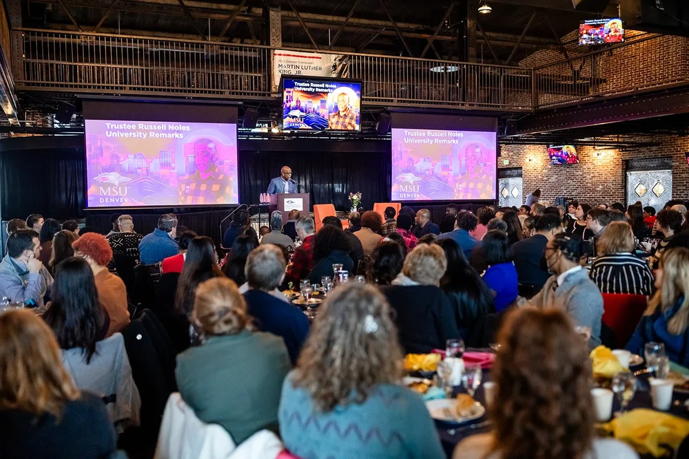 Trustee Russell Noles speaking at podium during MSU Denver MLK Peace Breakfast Mile High Station Denver full room