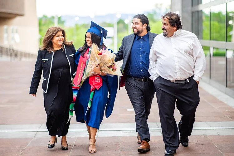 MSU Denver MSW graduate adjusting cap outside Buell Theatre Denver Performing Arts Complex