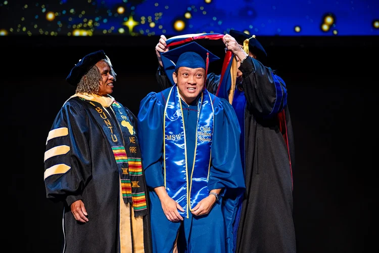 MSU Denver MSW graduate with decorated cap and HRSA Scholar stole outside ceremony Denver