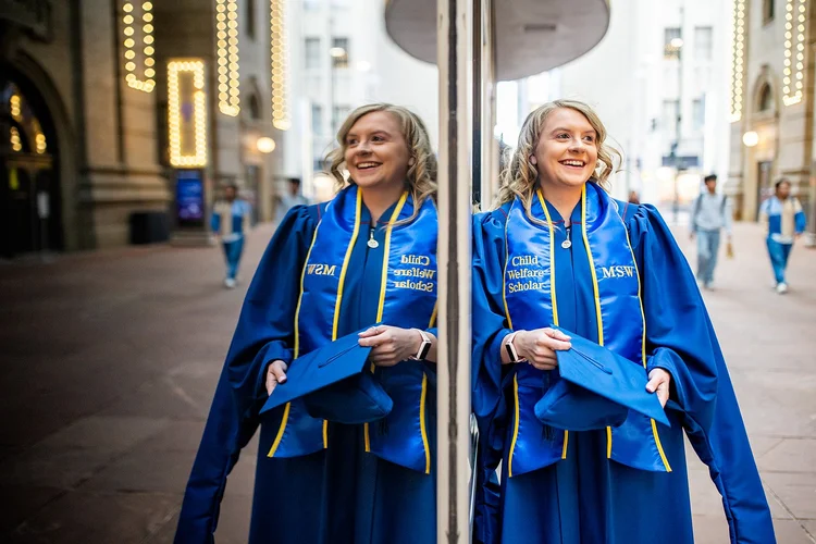 MSU Denver MSW graduate smiling in decorated cap seated in Ellie Caulkins Opera House Denver Colorado