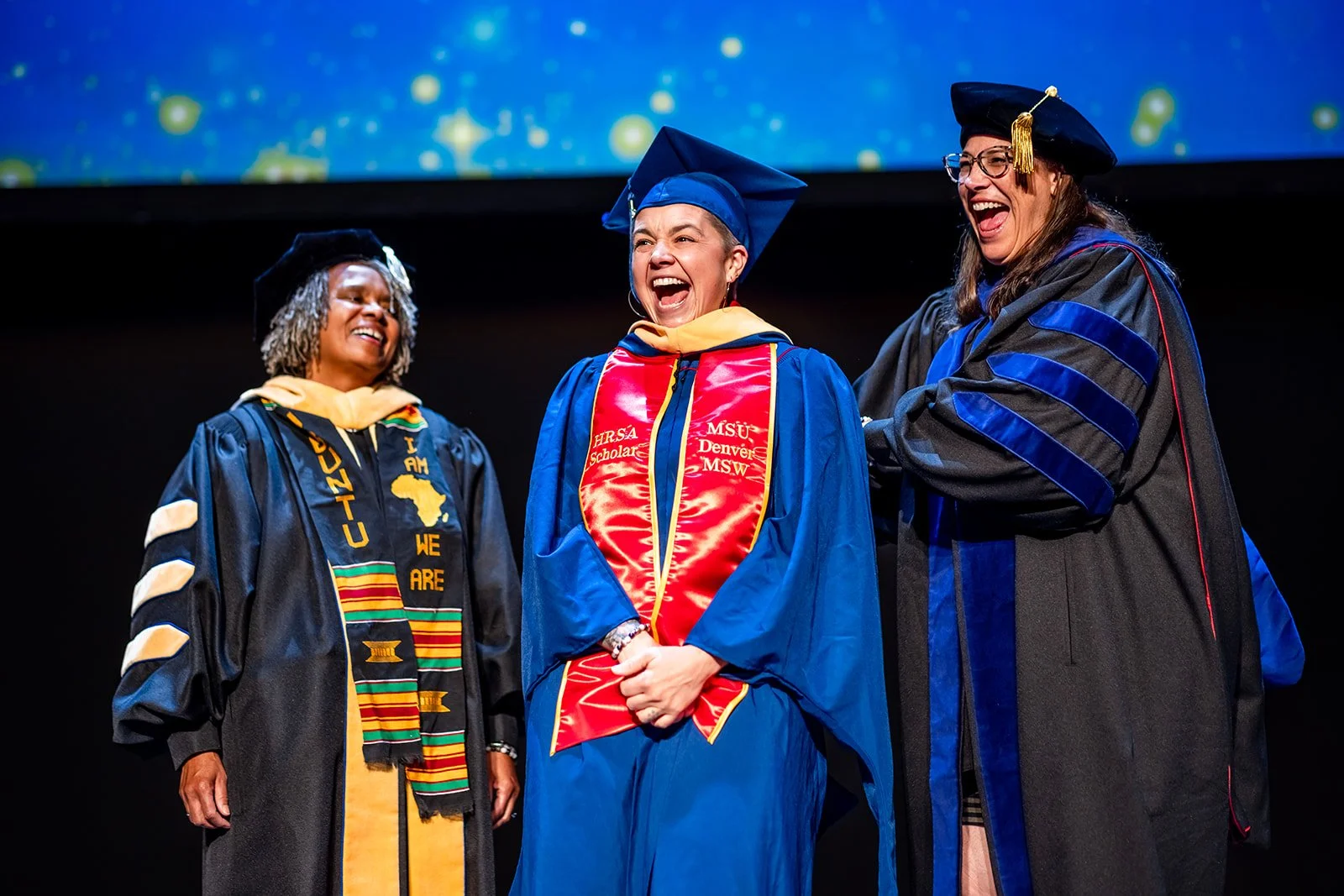 MSU Denver MSW graduate laughing during hooding ceremony on stage Ellie Caulkins Opera House Denver