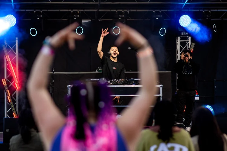 DJ performing at stage with crowd raising hands at Roadrunners After Dark MSU Denver