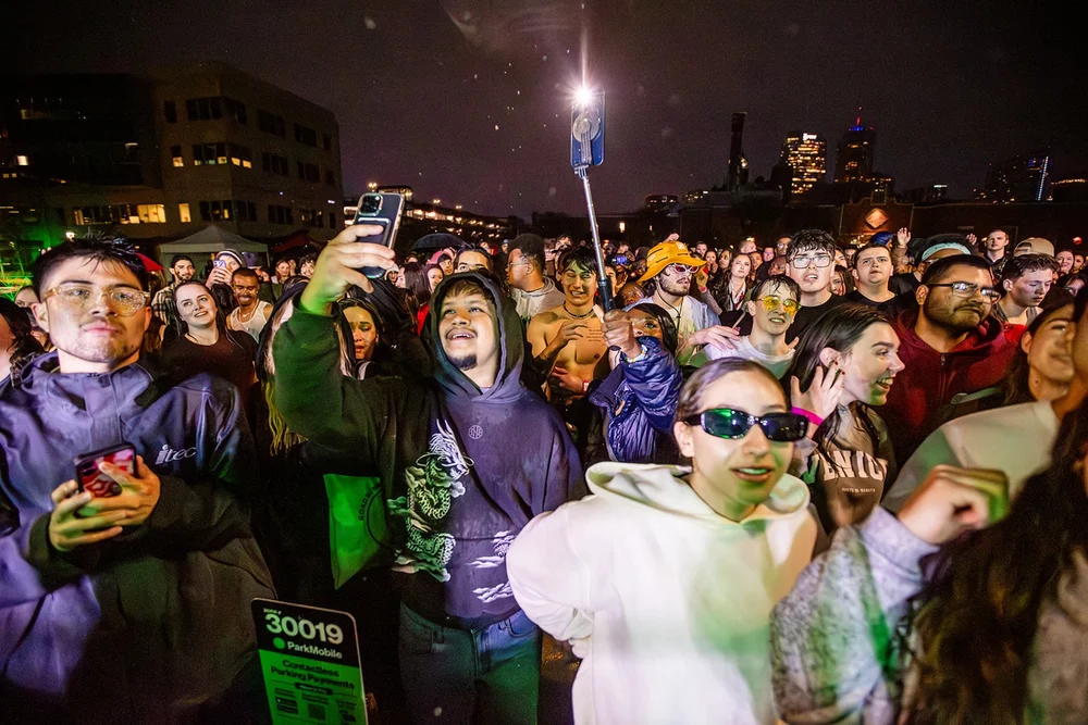 Large crowd with Denver skyline at night at Roadrunners After Dark MSU Denver concert