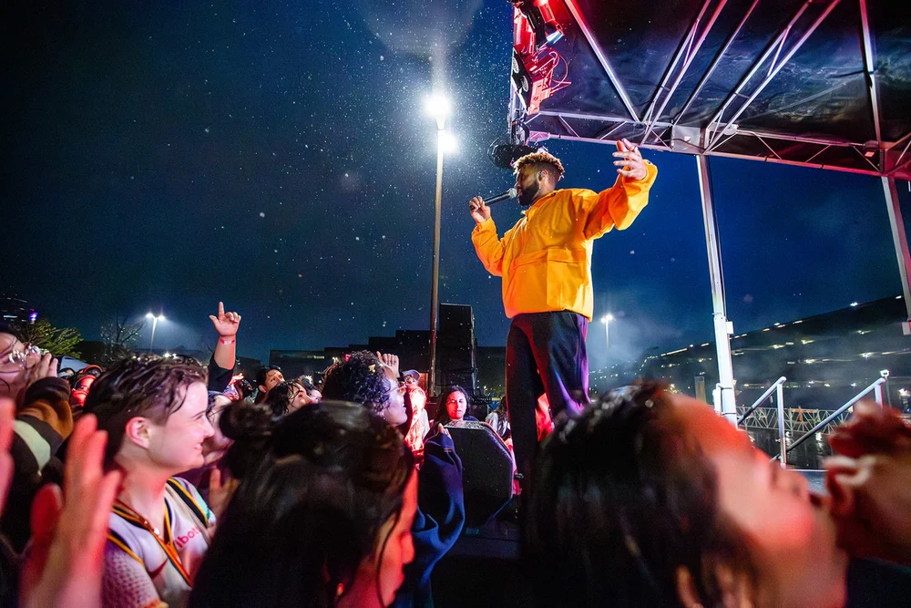 Performer on stage above the crowd at an outdoor concert in Denver