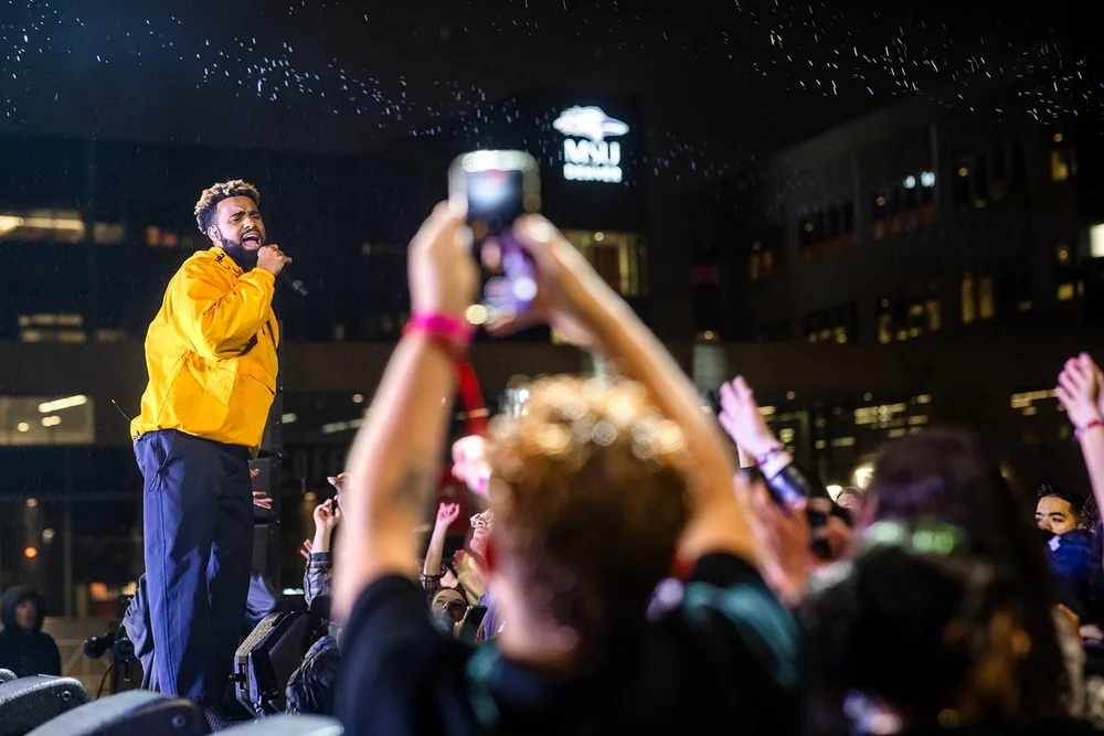 Headliner performer at Roadrunners After Dark concert with MSU Denver building sign behind him