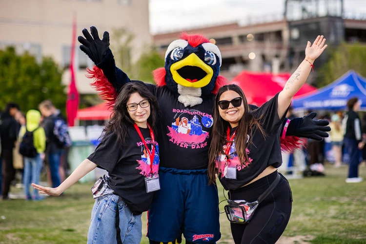 Two students in Roadrunners After Dark shirts posing with Rowdy mascot MSU Denver