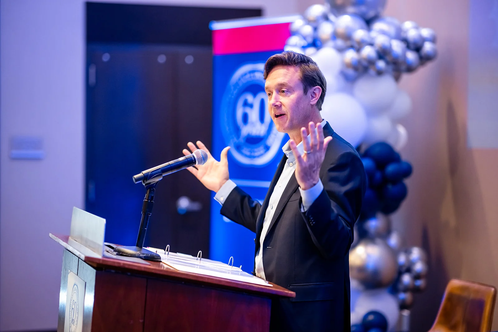 keynote speaker at podium with balloon arch at SpringHill Suites Denver corporate event