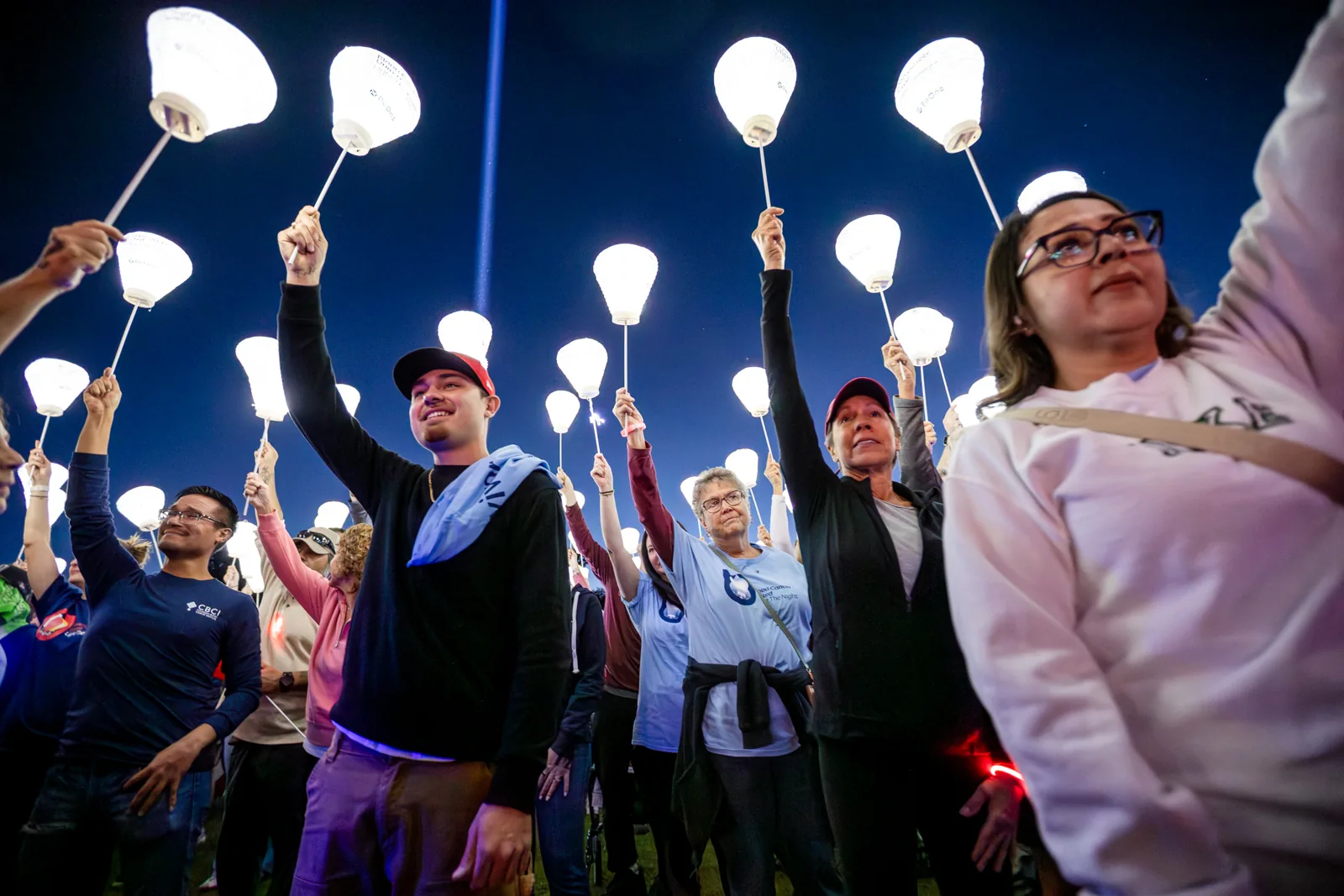 Supporters raising lanterns at a Light The Night nonprofit fundraising walk in Denver